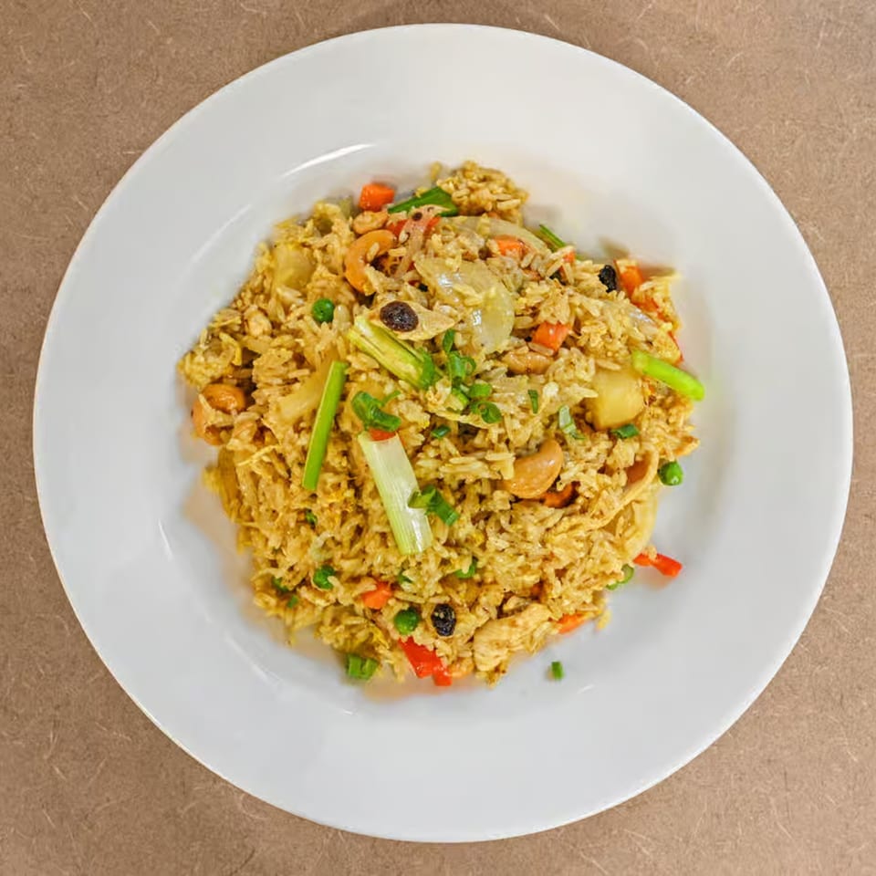 Truly Thai Restaurant's pineapple fried rice with cashews, raisins, and vegetables on a white plate.