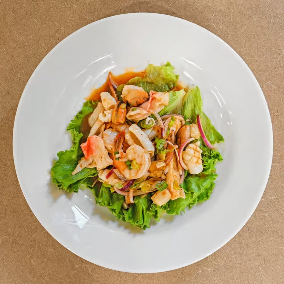 Truly Thai Restaurant's spicy seafood salad with shrimp, squid, mussels, and red onion on lettuce.