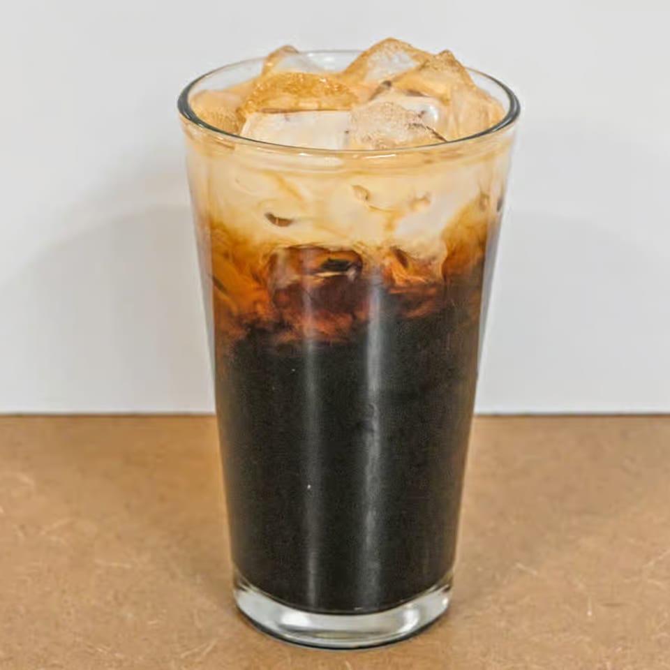 A tall glass of iced Thai tea with dark tea at the bottom and creamy milk on top.